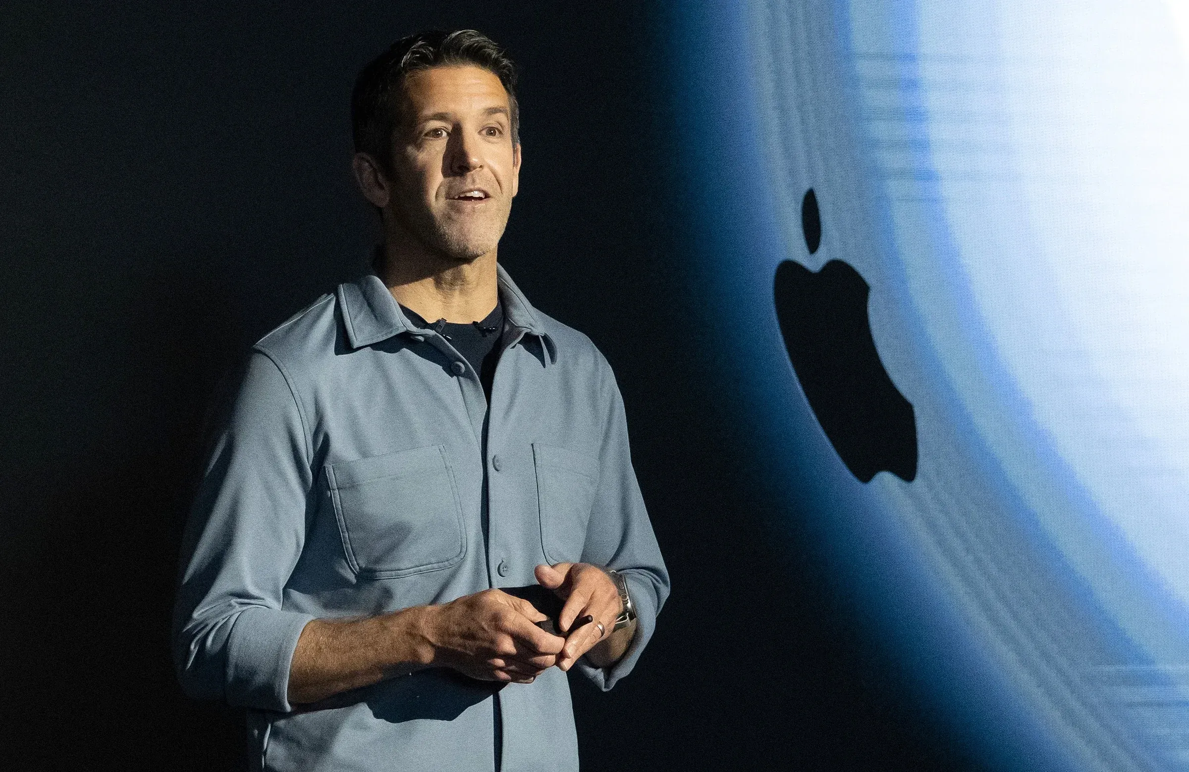 John Ternus, Senior Vice President of Hardware Engineering, thuyết trình tại sự kiện Apple trên nền logo Apple